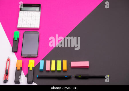 Bild der moderne Arbeitsplatz mit Rechner, Marker, Schreibwaren und Smartphone mit Copyspace auf rosa und schwarzen Hintergrund Stockfoto