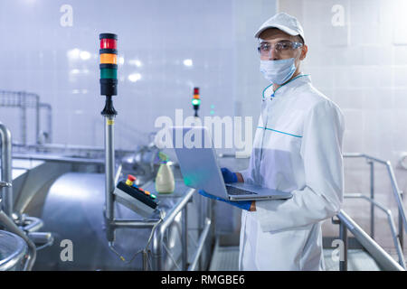 Ein Mitarbeiter mit einem Laptop in der Hand an der Milchfabrik Stockfoto