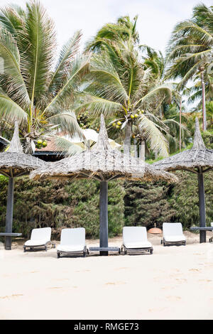 Liegestühle am Strand im Schatten der Reed in Vietnam gemacht Stockfoto