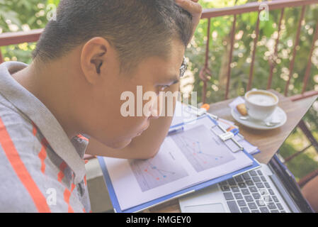 Müde und erschöpft asiatischer Mann mit Laptop Stockfoto