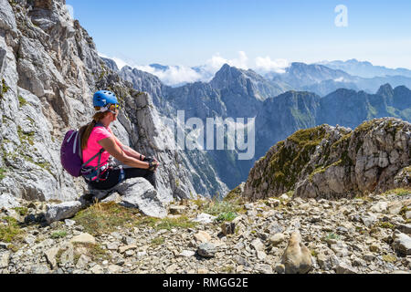 Junge Mädchen die Aussicht von einem Höhepunkt in den Julischen Alpen, Nationalpark Triglav, Slowenien, während einer Pause am Klettersteig Route, an einem heißen, hell, Su Stockfoto