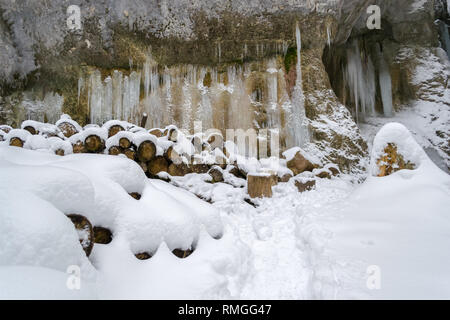 Gefrorenes Wasser Spalten auf einer Felswand, mit Baumstämmen zugeschnitten und mit frischem Schnee bedeckt - Szene Winter in sieben Leitern Canyon, Piatra Mare mounta Stockfoto