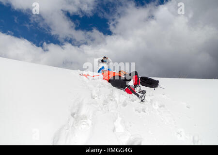 Zwei Frauen glücklich aber müde Wanderer eine Pause in knietiefem Schnee, während eines Winters Trekking Tour im Bucegi (Karpaten) Berge, Rumänien, gerade unter Stockfoto