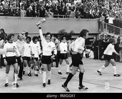 Franz Beckenbauer hält die WM-Trophäe als Kapitän der deutschen Fußball-Nationalmannschaft, nach dem 2-1 Sieg über Holland. Auf der rechten Seite ist sein Teamkollege Berti Vogts. Stockfoto