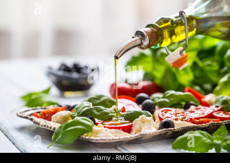 Gießen Olivenöl auf Caprese Salat. Gesunde italienische und mediterrane Speisen. Stockfoto