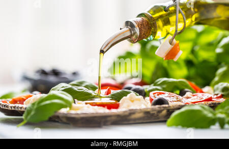 Gießen Olivenöl auf Caprese Salat. Gesunde italienische und mediterrane Speisen. Stockfoto