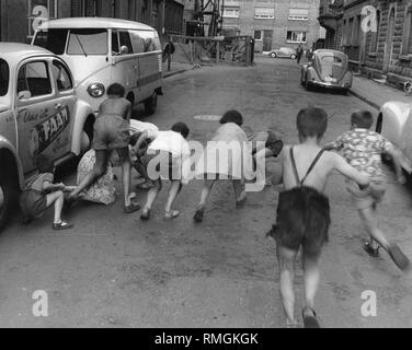 Eine Gruppe von Kindern spielt auf der Straße zwischen parkenden Autos und Baustellen. Stockfoto