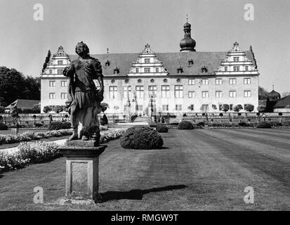 Blick durch den Garten auf der Vorderseite des Renaissance Schloss Weikersheim. Im Vordergrund steht eine steinerne Statue. Stockfoto