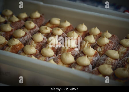 Frisch Krapfen gefüllt mit Vanillepudding auf den Verkauf in einer Bäckerei in einem lokalen Markt abgewürgt. Querformat. Stockfoto