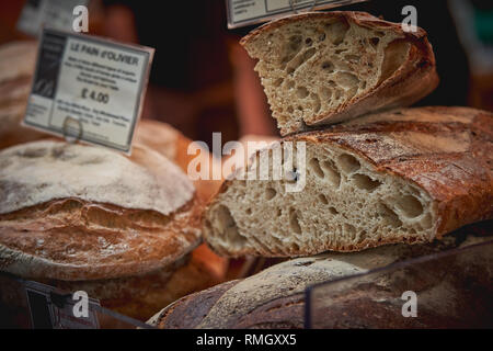 Stapel von organischen braunen und weißen Sauerteigbrot Brote auf den Verkauf in einem lokalen Bauernmarkt. Querformat. Stockfoto
