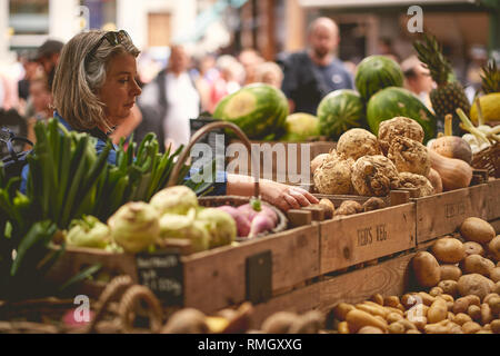 London, UK - Juni, 2018. Grüne Lebensmittel, einschließlich Kartoffeln, Wurzeln, Zwiebeln und exotische Früchte auf Verkauf zu einem Gemüse in Borough Market Stall. Stockfoto