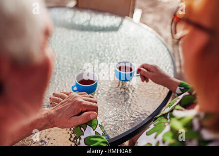 Senior paar Tee trinken im Hotel Cafe halten sich an den Händen. Glückliche Menschen genießen Urlaub. Close-up Stockfoto
