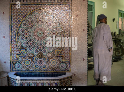 Bunte Antike Mosaiken im Stile im inneren Elemente. Arabisch marokkanischen Mann hören Trinkbrunnen in Marrakesch Stockfoto