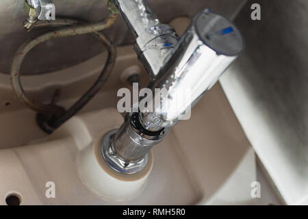 Undichte Rohre aus Stahl unter der Spüle mit Wassertropfen Stockfoto