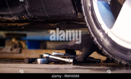 Car Service. Mechaniker Mann erreichen für ein Werkzeug. Hand in Arbeitshandschuh Stockfoto