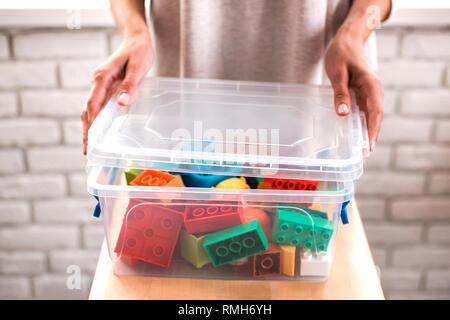 Die Frau Hände setzen farbige Bausteine in Box. Stockfoto