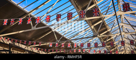 Großbritannien Flaggen an einem Kabel hängen von einem Dach aus Stahl mit Oberlichtern. Panoramaformat. Stockfoto