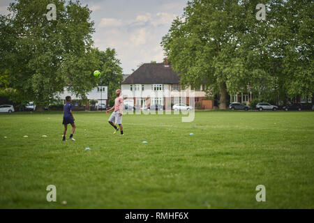 London, UK - Juni, 2018. Zwei junge Männer spielen Fußball in einem Park im Südosten von London. Stockfoto