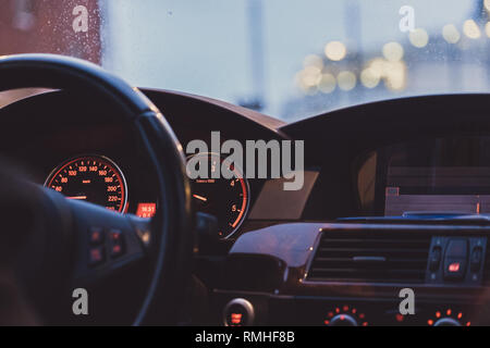 Künstlerische Innenansicht eines Auto mit Fokus auf die Messgeräte und den Wecker und bokhed Samenkapseln in der Windschutzscheibe Stockfoto