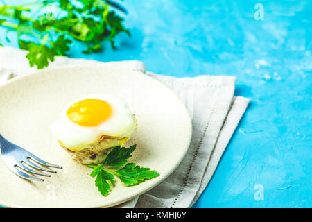 Gebackene Eier in der Licht- und Backformen. Portioniert Auflauf von Speck und Eier im italienischen Stil. Blauer Beton Tischfläche Hintergrund. Stockfoto