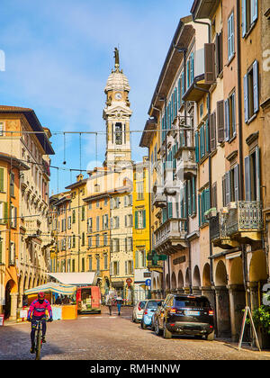 Ein Radfahrer Kreuzung Piazza Pontida Quadrat mit dem Glockenturm der Basilika St. Alexander in Spalte im Hintergrund, bei Bergamo, Bergamo. Stockfoto