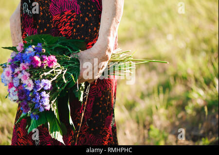 80-jährige Frau mit einem Blumenstrauß in der Hand. Stockfoto