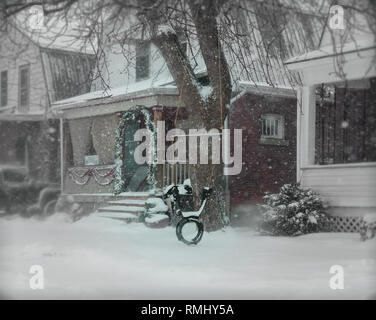 Eine malerische Straße, einen Gehweg mit Schnee bedeckt. Wir sehen ein Reifen auf einem Zweig hängend, aus dem Baum vor dem Haus. Ein kalter Tag Grau des Winters. Stockfoto