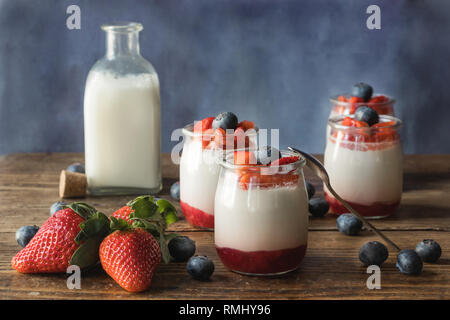 Immer noch leben der hausgemachten Joghurt mit Erdbeermarmelade und Stück Obst auf einem Holzbrett Stockfoto