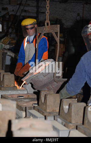 Gießer geschmolzenes Eisen in Formen für die Herstellung von Gitterrosten Feuer gießen Stockfoto