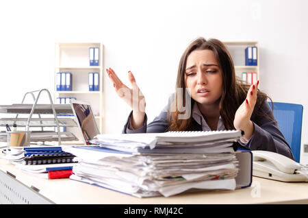 Junge weibliche Mitarbeiter mit übermäßiger Arbeit unzufrieden Stockfoto