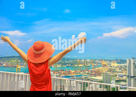 Sorglos Frau genießt Panorama von einem der höchsten Wolkenkratzer in Singapur Chinatown. Luftaufnahme der Insel Sentosa und Keppel Harbour. Lifestyle w Stockfoto