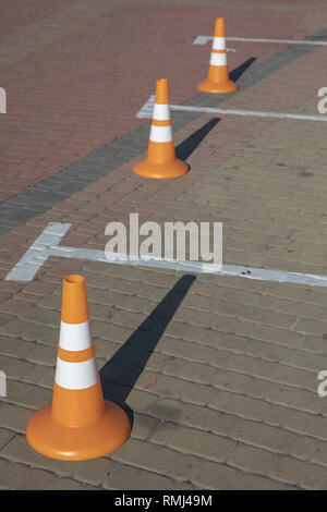 Orange Kegel stehen in einer Reihe in der Nähe der Parkplätze Stockfoto