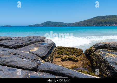 Blick über Felsen am Kiesstrand, ein beliebter Campingplatz mit großen Surfing Beach und Buschwanderungen im Murramarang National Park, NSW, Australien Stockfoto
