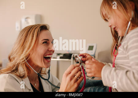 Weibliche Patienten Arzt und Mädchen spielen mit Stethoskop in der Klinik. Freundlich Kinderarzt mit Mädchen Patienten an der Klinik. Stockfoto