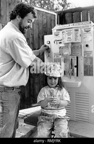 Tanja mit ihrem Vater vor einem Self-service-Softeis Maschine. Während die Mädchen bereits ist ihr Eis halten sie in ihrer Hand, der Vater wirft Münzen in der Maschine für eine weitere Portion Eis. Stockfoto