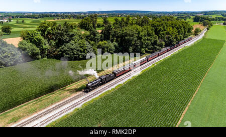 Luftaufnahme von Dampf Personenzug Puffing Rauch in Amish Landschaft an einem sonnigen Frühlingstag Stockfoto