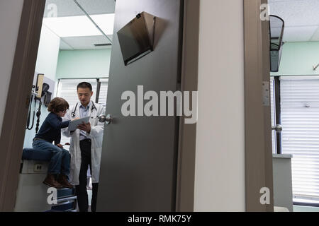 Jungen asiatischen männlicher Arzt und kaukasische junge Patienten mit digitalen Tablet in der Klinik Stockfoto