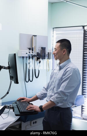 Jungen asiatischen männlicher Arzt Arbeiten am Computer in der Klinik Stockfoto