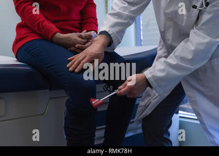 Jungen Asiatischen männlicher Arzt prüft ein älterer Patient mit reflexhammer in der Klinik Stockfoto