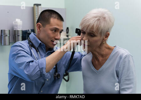 Jungen Asiatischen männlicher Arzt prüft ein älterer Patient in der Klinik Stockfoto