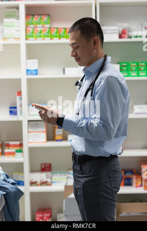 Jungen Asiatischen männlicher Arzt holding Medizin und stehen in der Klinik Stockfoto