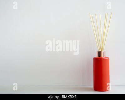 Lufterfrischer stick rot Flasche auf weiße Wand Hintergrund mit kopieren. Aromatische reed Stick in modernen Flasche. Stockfoto