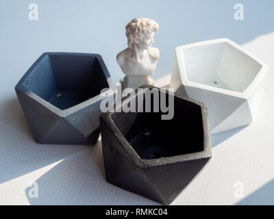 Moderne geometrische Pentagon konkrete Pflanzmaschinen mit kleinen David Statue auf weißem Hintergrund. Malte konkrete Töpfe für Dekoration, minimalistischen Stil eingerichtet. Stockfoto