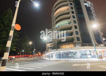 MOUNT MAUNGANUI NEUSEELAND - 7. FEBRUAR 2019: Apartments und Cafés der Marine Parade Ecke an der Basis der Straße von Straßenlaternen beleuchtet montieren Stockfoto