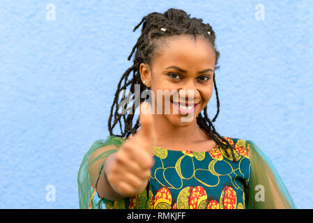 Enthusiastisch motivierten afrikanischen jungen Frau, ein "Daumen hoch" Geste der Anerkennung und Erfolg mit einem strahlenden Lächeln Stockfoto