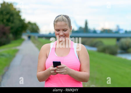 Outdoor Portrait der blonde junge lächelnde Frau mit Handy Stockfoto