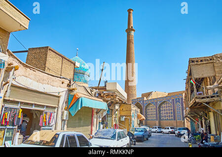 ISFAHAN, IRAN - 21. Oktober 2017: Die schäbige Straße von Grand (Qeysarie, Soltani) Basar mit Ständen und in alten Hütten und hohen Minarett des entfernt Geschäfte Stockfoto