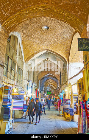 ISFAHAN, IRAN - 21. Oktober 2017: Die schmalen langen Korridor von textilen Abteilung des Grand (soltani) Basar mit alten Ziegelgewölbe und Ständen auf beiden Sid Stockfoto