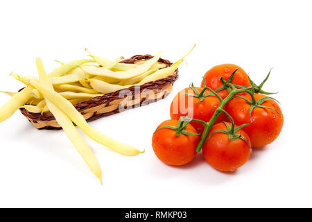 Gelb Holz- korb mit jungen Hülsen von Bohnen mit Bohnen und Bündel der frischen roten Tomaten mit Wassertropfen auf weißem Hintergrund Stockfoto