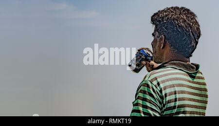 Im mittleren Alter asiatischer Mann in seiner Mitte der 50er Jahre tragen gestreifte T-Shirt, und in tiefer denken, während sie sein Getränk oder Bier aus Aluminium. Stockfoto